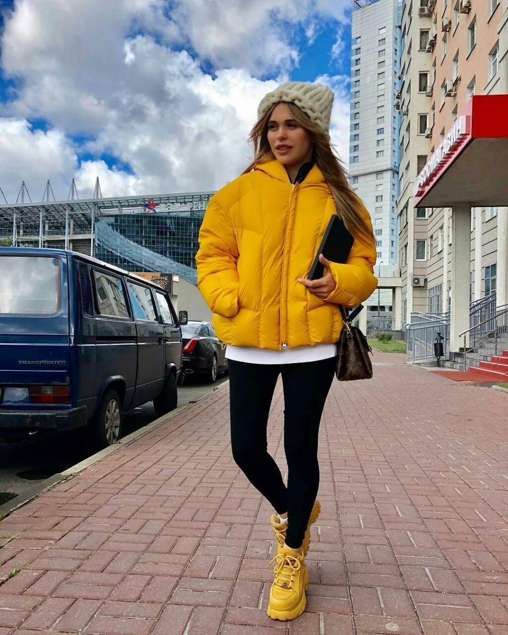 Желтая пуховая куртка с черными лосинами и желтыми ботинками